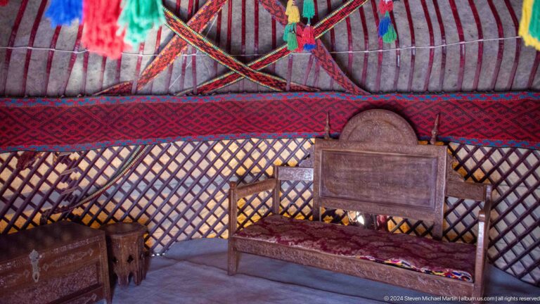 Reconstructed yurt interior with bed and textiles.