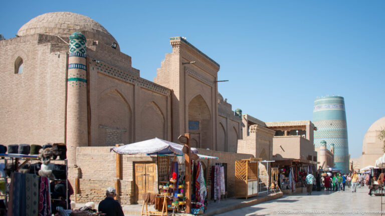Market stalls beside a monumental brick portal and kalta minor.