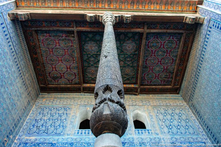 Carved wooden column rising to painted ceiling.