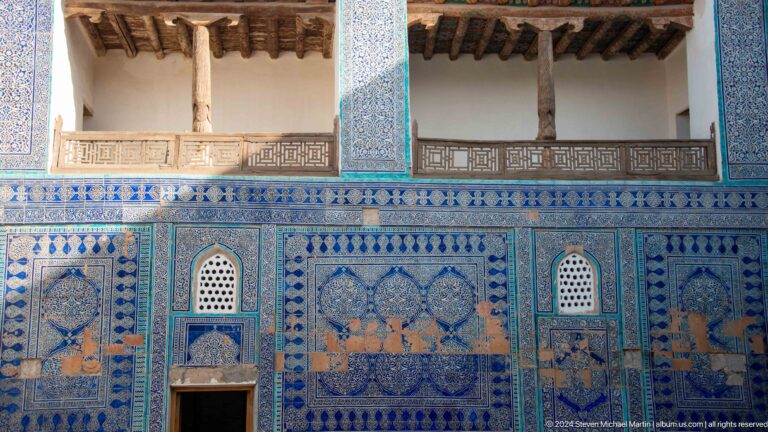 Ornate blue-tiled wall with doors and niches.