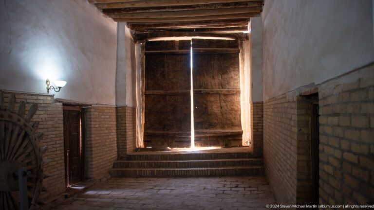 Dark interior passage with light through wooden shutters.