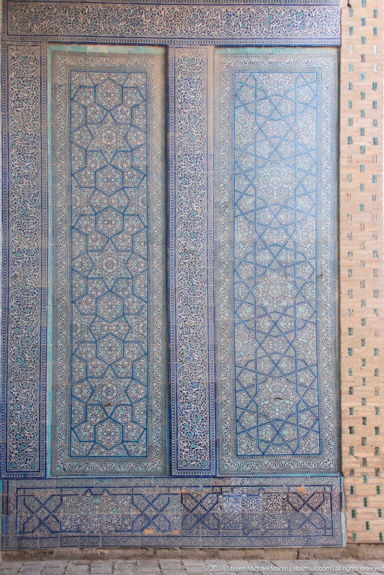 Vertical blue geometric tile borders on brick wall.