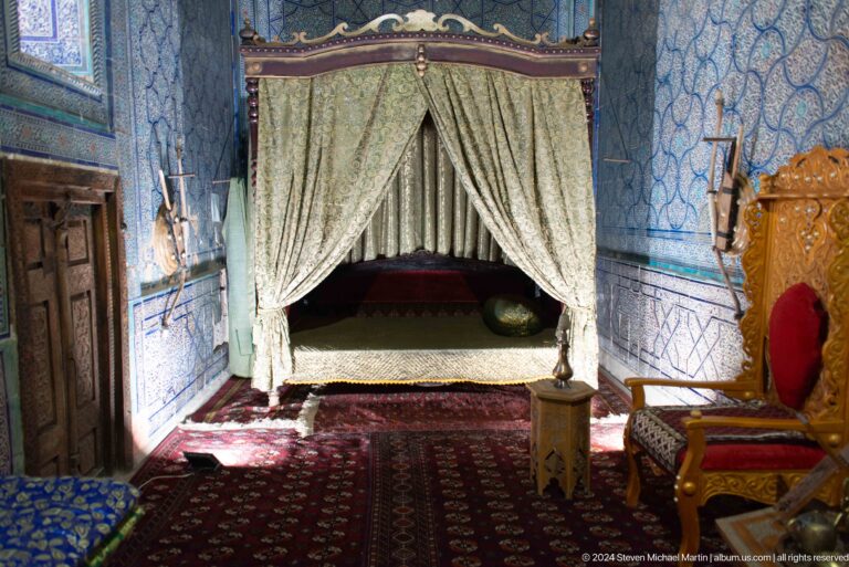 Canopied bed in richly decorated chamber.