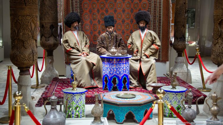 Wax figures in traditional robes around ceremonial table.