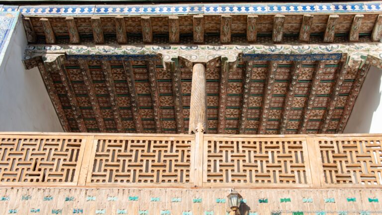 Carved wooden balcony and ceiling supported by column.