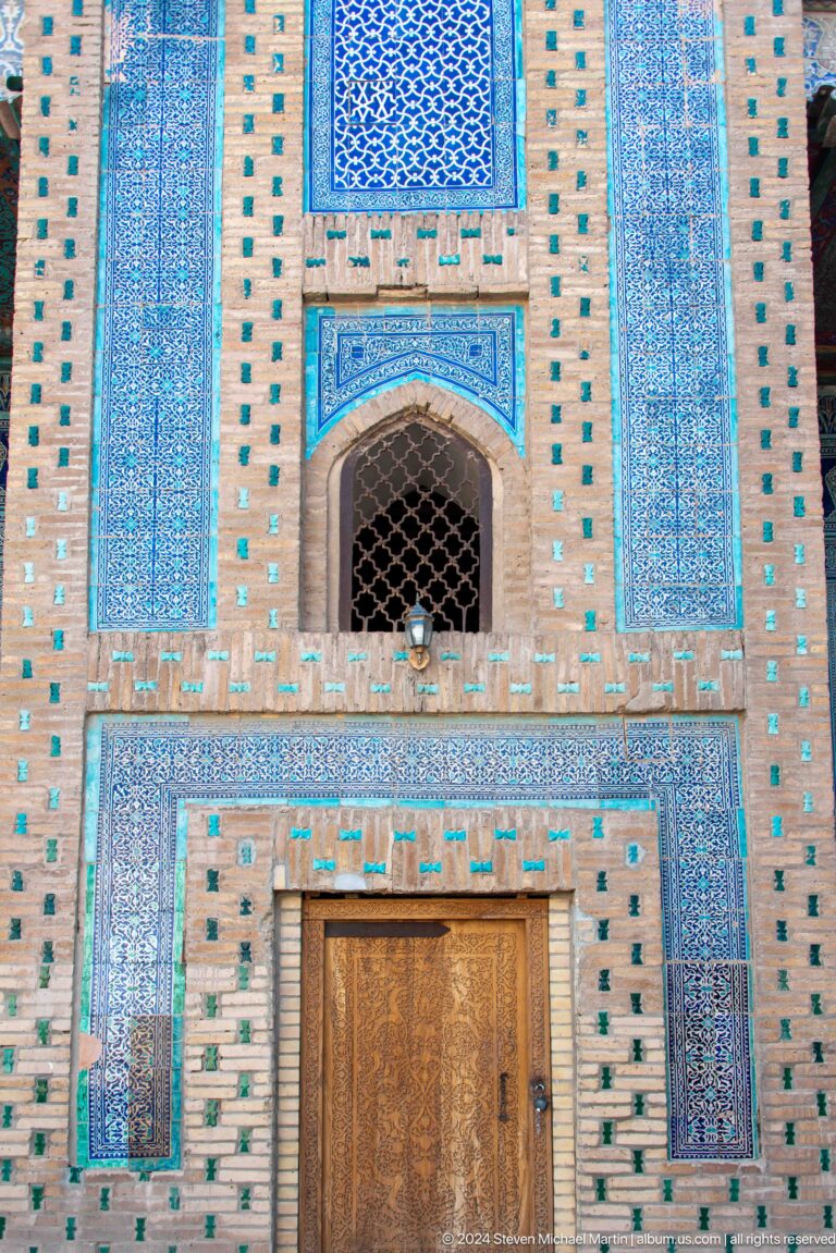 Turquoise tiled wall with pointed lattice window.