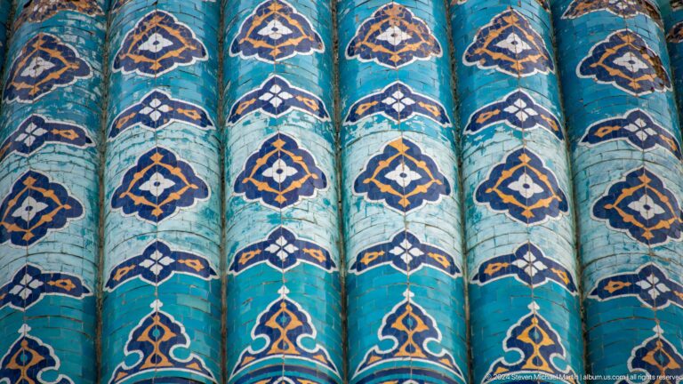 Close-up of turquoise fluted dome ribs decorated with repeated dark-blue, white, and ochre motifs.