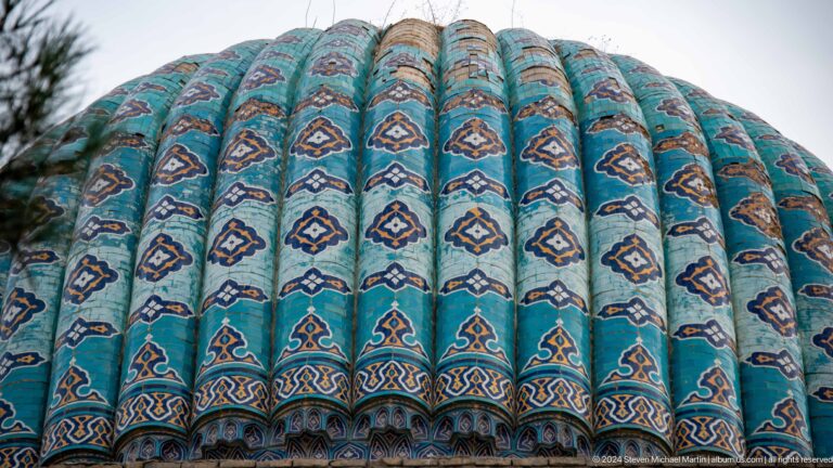 Lower edge of a turquoise ribbed dome with repeating motifs and a patterned transition band.