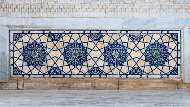Horizontal tile panel with repeated blue star polygons inside a dark interlaced geometric lattice.