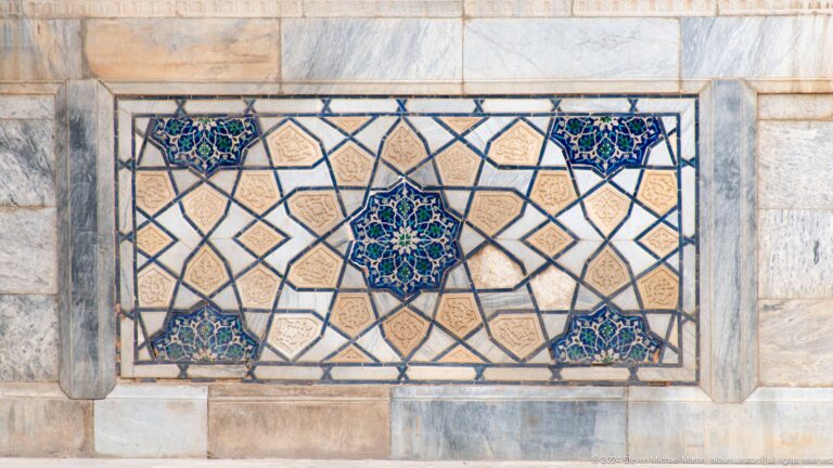 Rectangular tile panel with a central blue-green star medallion, angular lattice, and four smaller corner motifs.