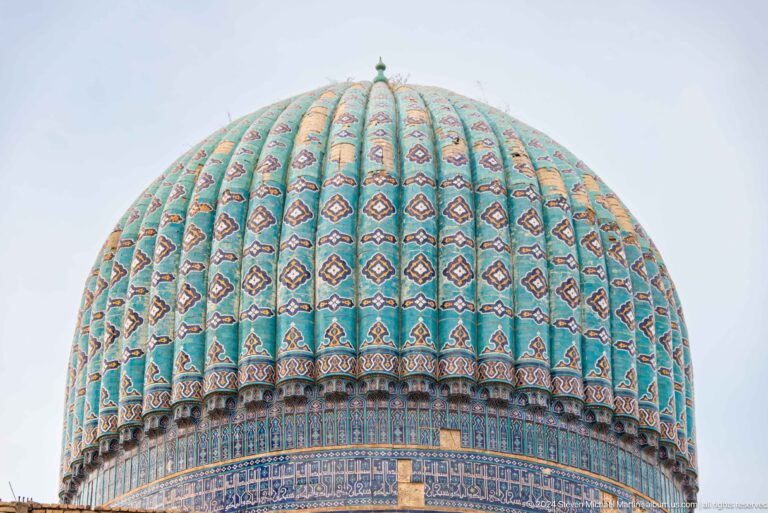 Turquoise ribbed dome with patterned vertical bands, a small finial, and a dark-blue decorated base.