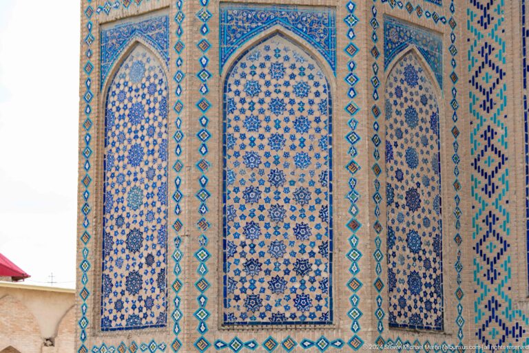 Corner façade with tall pointed blue patterned tile panels and narrow turquoise geometric borders.