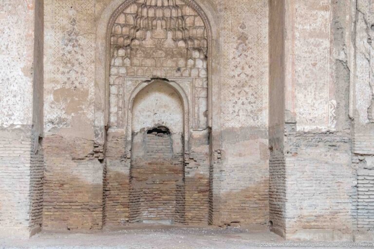 Weathered interior wall niche with exposed brick repairs, worn plaster, and a smaller pointed recess.