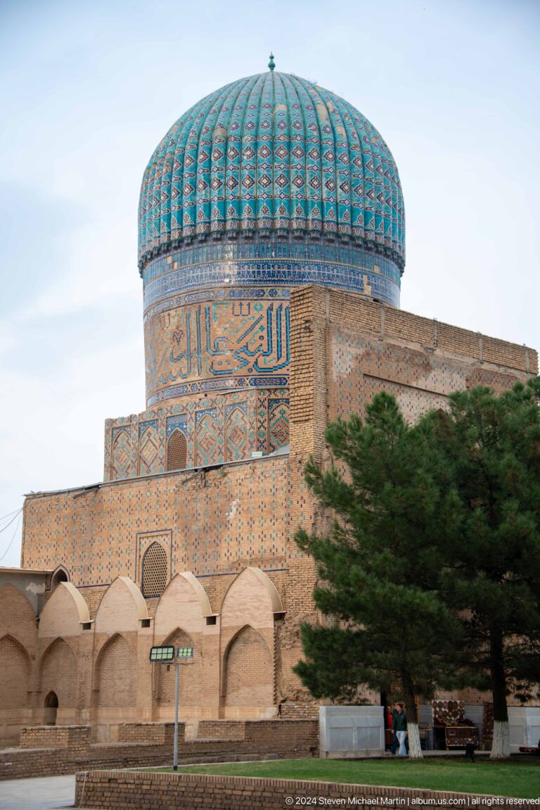 Angled close view of a decorated cylindrical tower above a projecting plain brick corner.