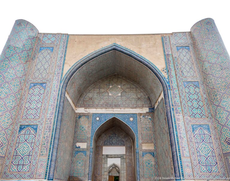 Steep upward view of the monumental pointed iwan framed by turquoise and blue tile panels.