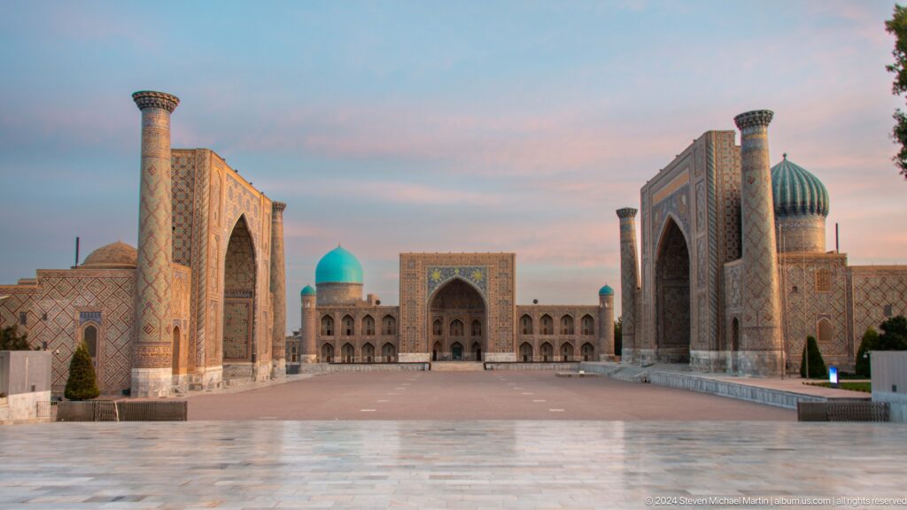 Wide dusk view of Registan Square with three monumental madrasas, turquoise domes, and minarets.