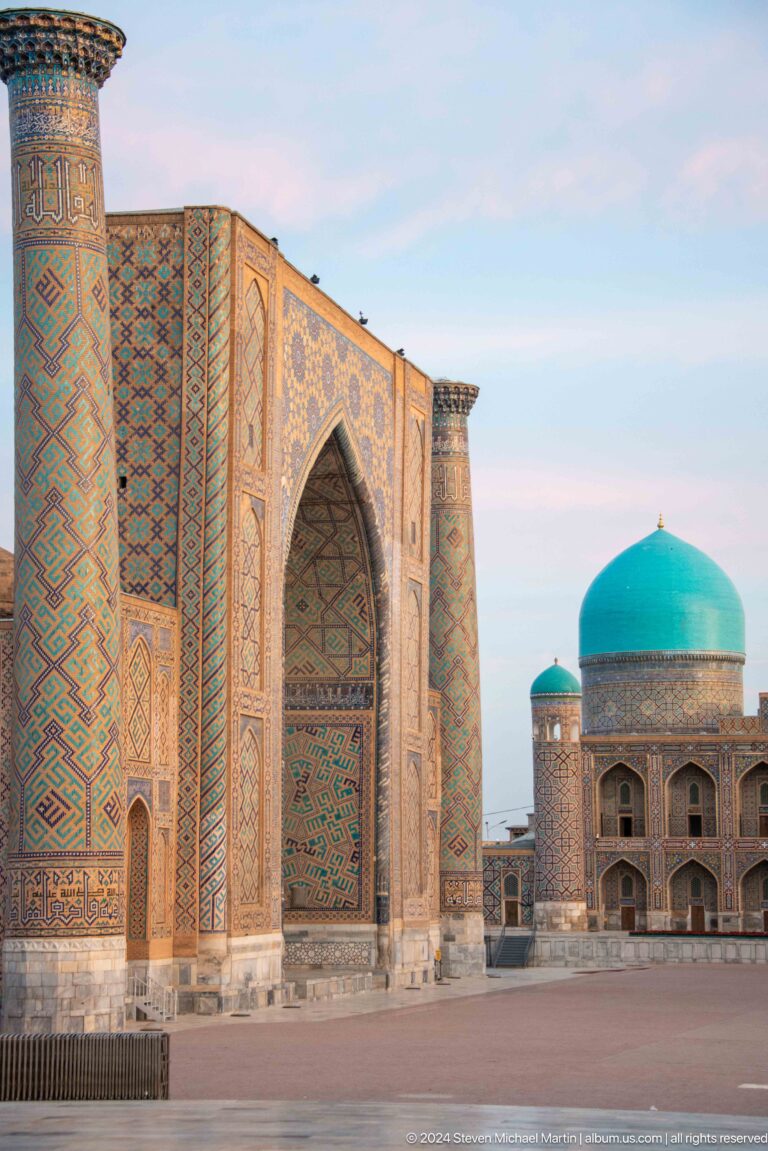 Oblique view of Ulugh Beg Madrasa portal with a turquoise dome visible beyond.