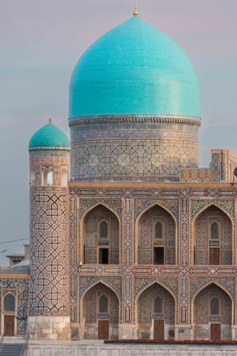 Turquoise dome above a patterned drum and a row of pointed arches at Tilya-Kori Madrasa.