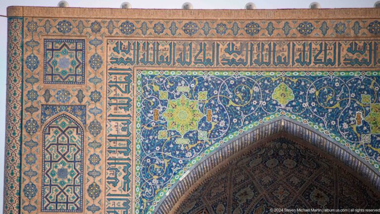 Arabic inscription band above a pointed arch surrounded by blue floral tilework.