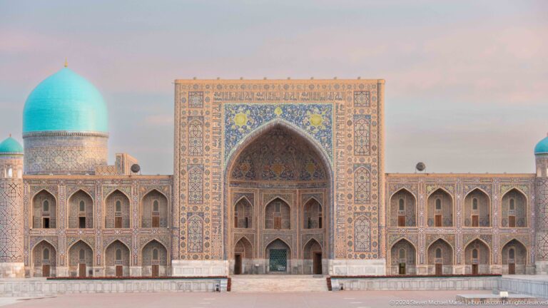 Frontal view of Tilya-Kori Madrasa with a large tiled portal, arcaded wings, and a turquoise dome.