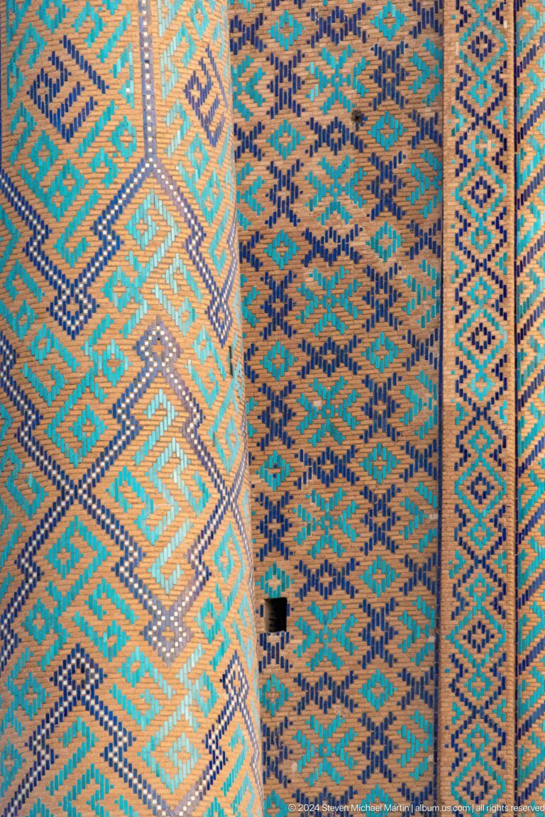 Close-up of turquoise, orange, white, and blue interlocking geometric tilework.