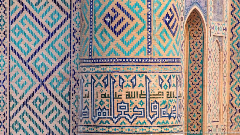 Turquoise geometric tilework with a horizontal Arabic inscription panel and a small pointed recess.