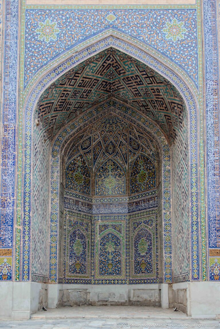 Upward view into a deep pointed portal vault covered in blue, white, and ochre ornament.