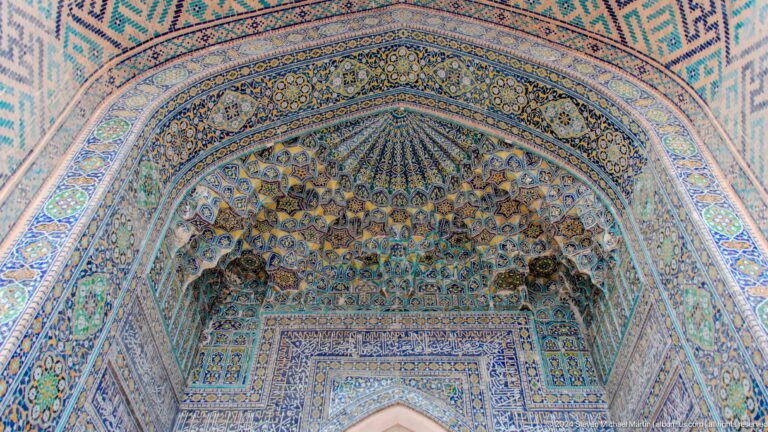 Close upward view of a radial muqarnas crown in blue, turquoise, and ochre.