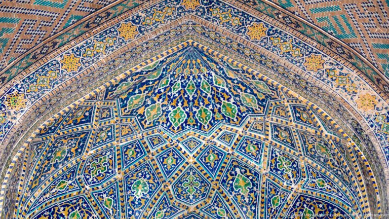 Close view of blue, turquoise, gold, and white geometric ornament covering a curved vault.