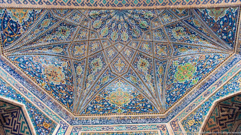 Upward view of a complex blue, turquoise, white, and ochre star-patterned vault.