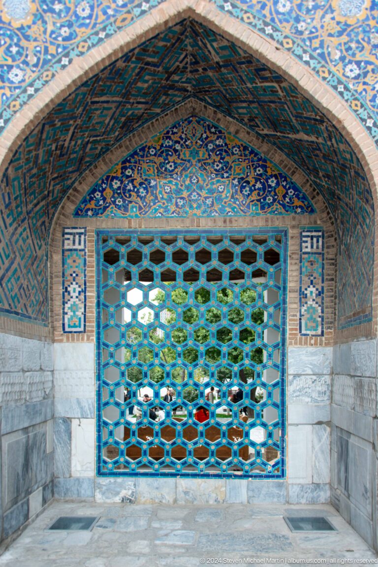Blue hexagonal lattice screen set within a turquoise tiled pointed recess.