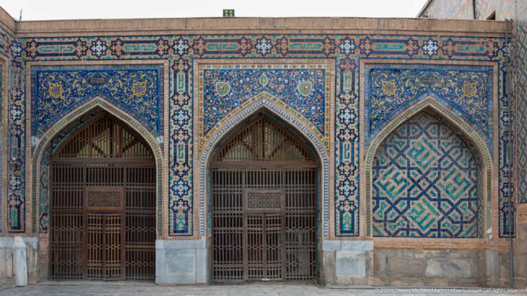 Three tiled pointed bays with wooden grilles and patterned infill panels.