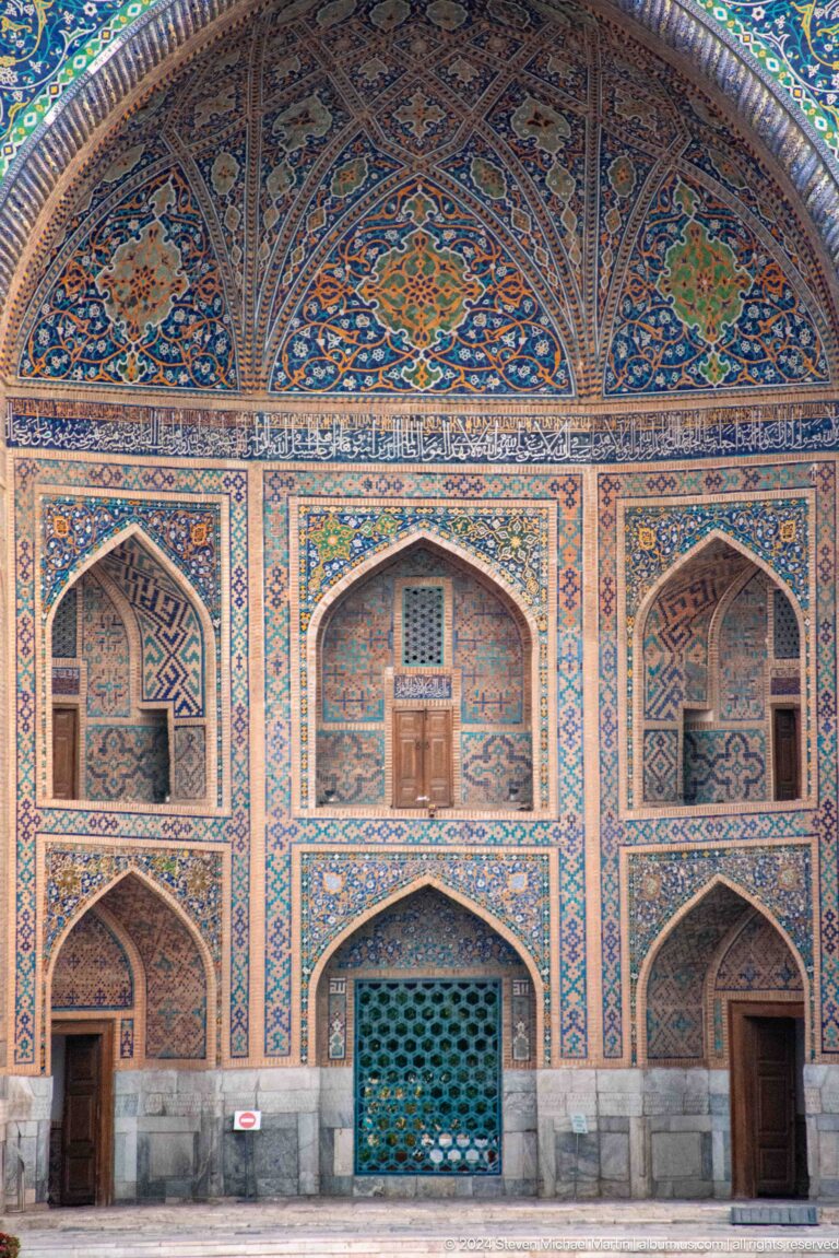 Three tiled pointed arches with a central wooden door on the Tilya-Kori Madrasa façade.