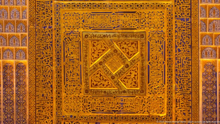 Close-up of a carved wooden panel with a central diamond motif and dense ornamental borders.