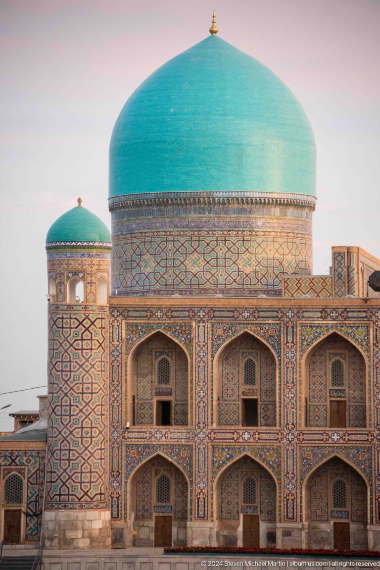 Turquoise dome above a patterned cylindrical drum and arched façade at Tilya-Kori Madrasa.