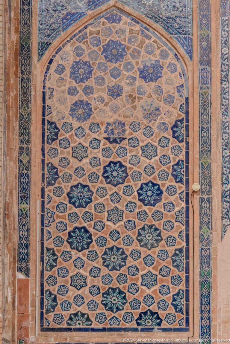 Close-up of blue, turquoise, white, and ochre geometric tilework with star and floral motifs.