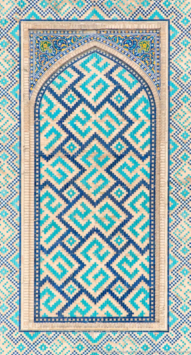 Close-up of a turquoise and dark blue stepped-diamond tile pattern with narrow borders.