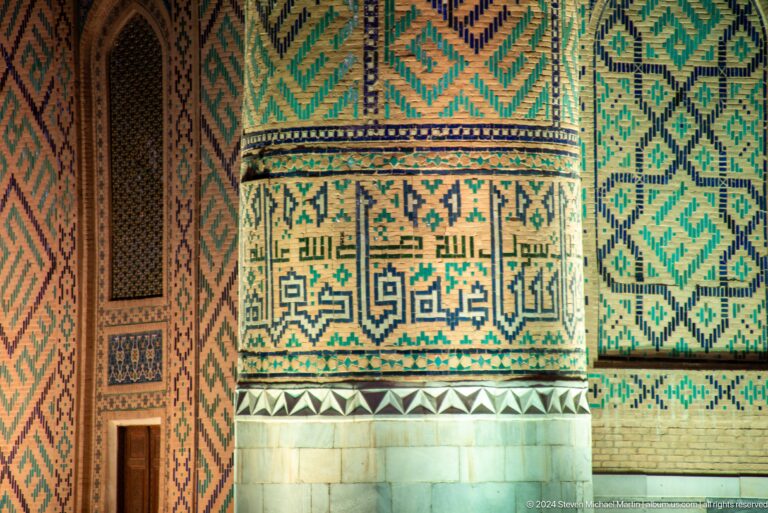 Close-up of turquoise geometric and calligraphic tilework beside a narrow doorway and pale stone base.
