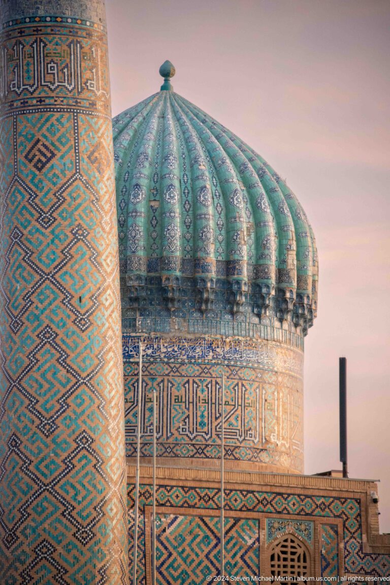 Ribbed turquoise dome behind a tiled minaret with bold geometric patterns.
