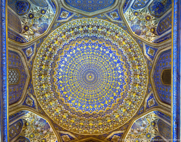 Centered upward view of a richly gilded blue-and-gold dome ceiling with radiating floral geometry.