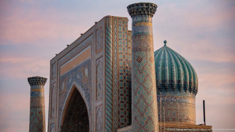 Oblique view of Sher-Dor Madrasa with monumental portal, tiled minaret, and ribbed turquoise dome.