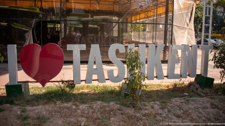 Red heart and large white TASHKENT letters outdoors beside a construction enclosure.