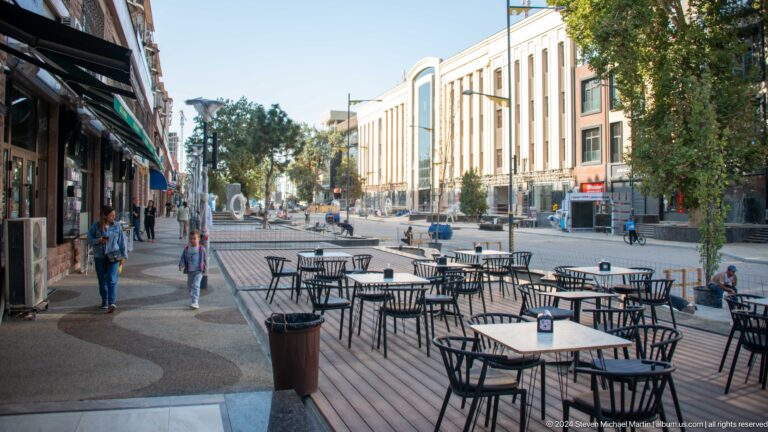 Outdoor cafe tables along a broad Tashkent pedestrian boulevard facing a modern building.