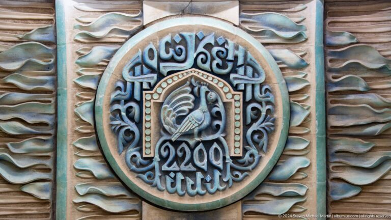 Round ceramic medallion with a stylized bird, ornamental border, and the number 2200.