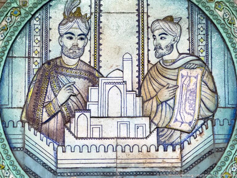Close ceramic detail of two bearded men holding a fortified city model and illustrated scroll.