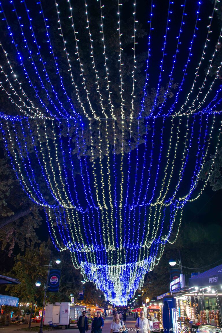 Upward view of converging blue and white decorative light strings.