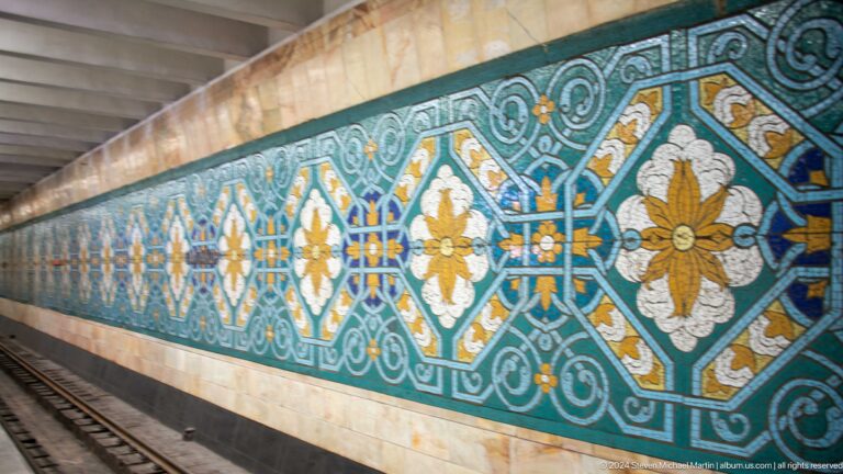 Turquoise floral mosaic frieze set into a polished stone wall in the Tashkent Metro.