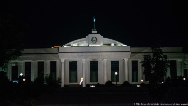 White symmetrical civic building with columns and a central pediment at night.