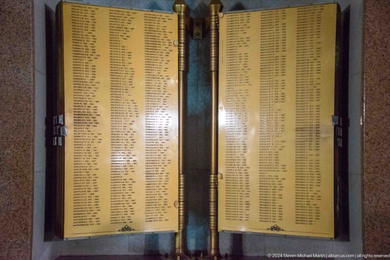 Close frontal view of two golden memorial pages densely covered with columns of names.