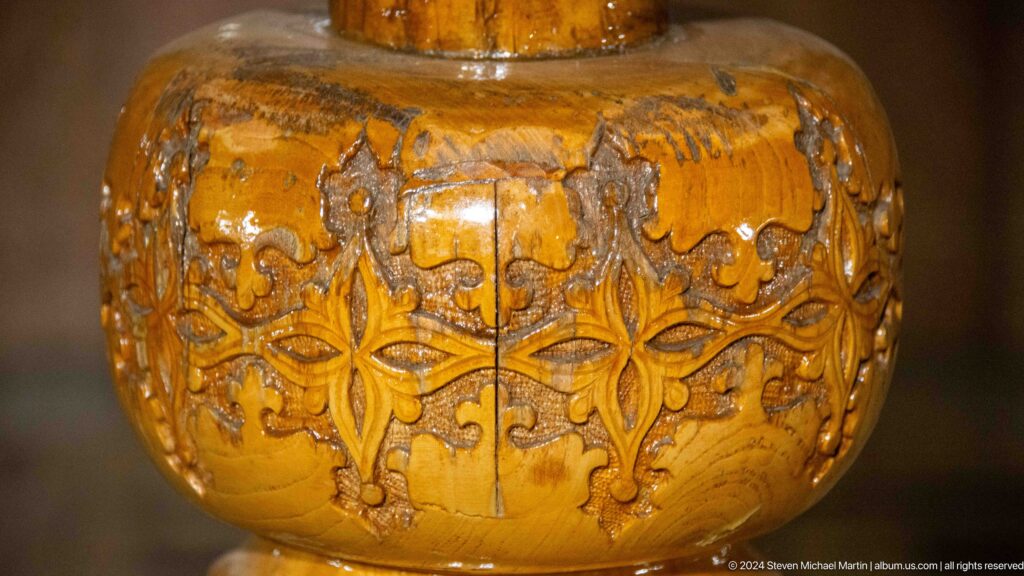 Rounded polished wooden element carved with birds, foliage, and scrolling ornament.